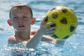 Closeup Portrait of a boy in the swimming pool with a football